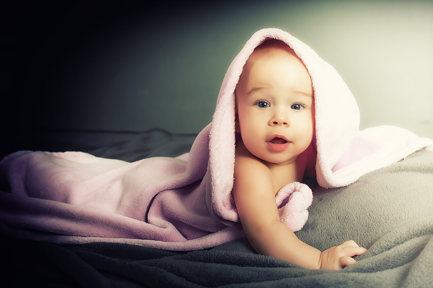 Ein Baby liegt unter einem Handtuch und schaut neugierig heraus
