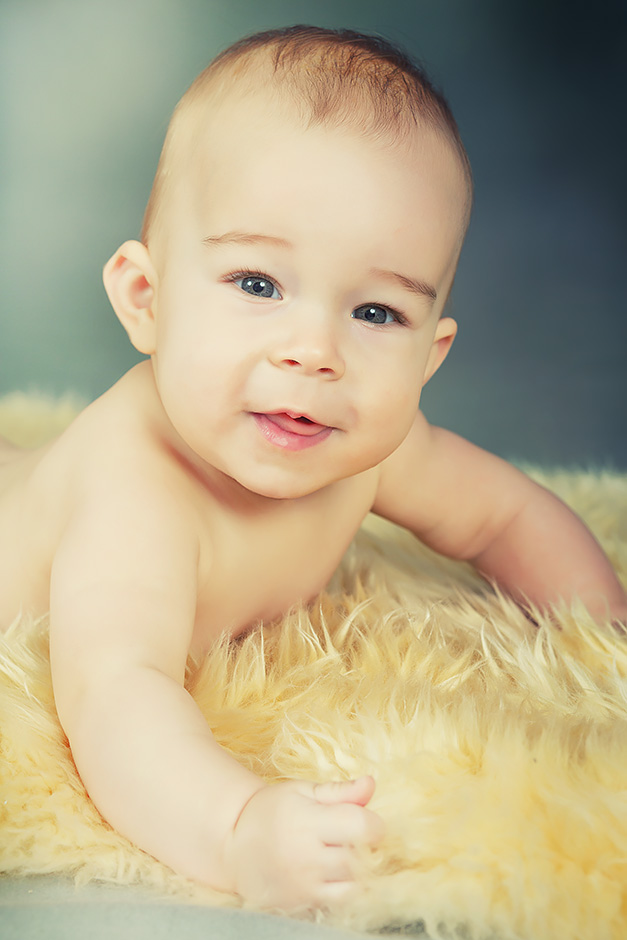 Ein Baby liegt auf einem Lammfell und lächelt