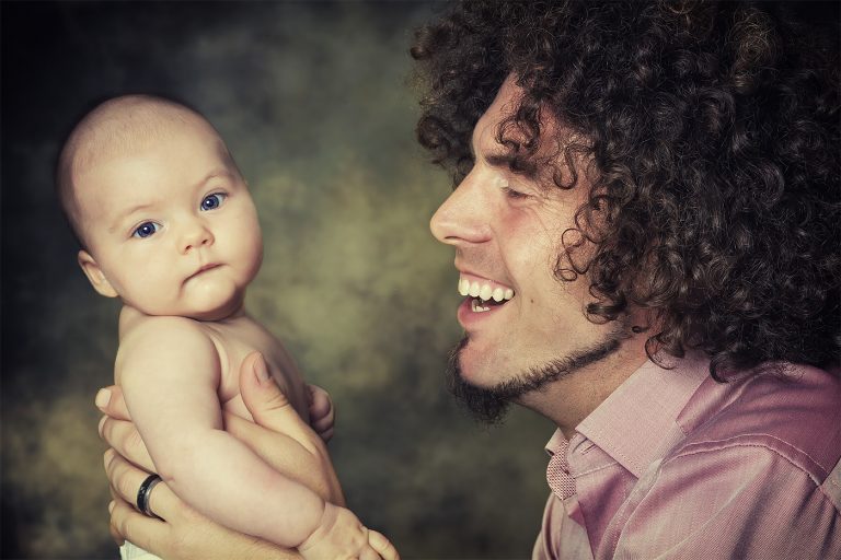 Ein Vater hält seinen Saeugling vor sich in den Händen